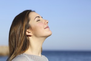 Woman profile portrait breathing deep fresh air on the beach with the ocean in the background